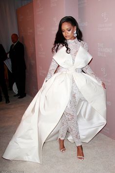 a woman in a white gown and high heels standing on the carpet at an event