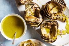 artichokes on plates with dipping sauce next to them