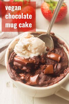 a bowl filled with chocolate pudding and ice cream next to two strawberries on the table