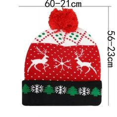 a red and white knitted hat with reindeers on it, next to the measurements