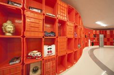 an orange shelf with many different items on it in the middle of a room filled with orange shelves