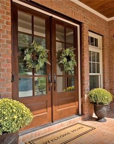 two potted plants sitting on the side of a brick building next to a door