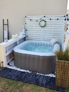 an inflatable hot tub sits outside on the lawn next to a potted plant