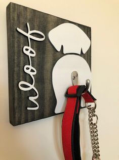 a wooden sign with a red leash hanging from it's side on a wall