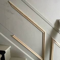 a stair case with two pictures on the wall and a clock hanging from it's side