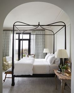 a bedroom with a four poster bed and white walls