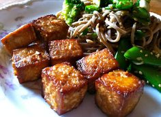 a plate with tofu, broccoli and noodles on it next to a fork