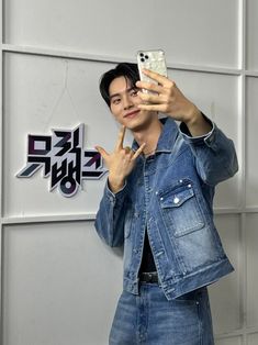 a man taking a selfie in front of a wall with stickers on it