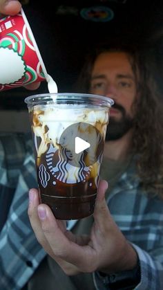 a man pouring coffee into a cup with whipped cream on top and toppings in it