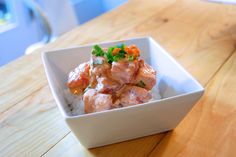 a white bowl filled with food on top of a wooden table