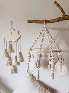 a wall hanging with shells, tassels and other things on it next to a pillow