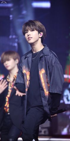 the young man is walking down the runway with his hand on his hip and wearing a black jacket