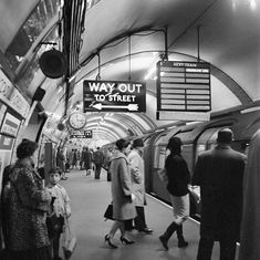 black and white photograph of people waiting for the subway to stop at it's station