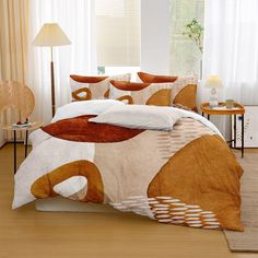 a bed covered in a brown and white comforter next to a table with a lamp