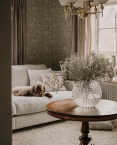 a living room filled with furniture and a chandelier hanging from the ceiling over a coffee table