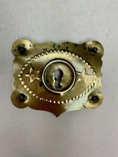 an ornate brass door handle with a keyhole and rivets in the center