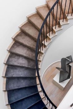 a spiral staircase with blue and grey carpet on the bottom, next to a white wall