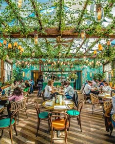 people sitting at tables in a restaurant with green plants growing on the walls and ceiling