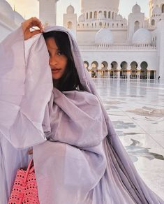 a woman is standing in front of a white building