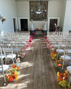 rows of white chairs with flowers on them in an indoor ceremony room at a stately venue