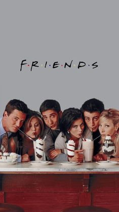 friends sitting at a table with cake and milkshakes in front of their faces