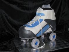 a cake shaped like a roller skate with blue and white wheels on a black background