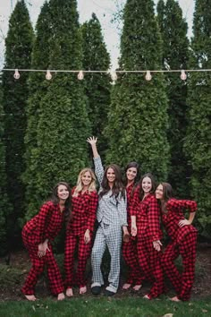 a group of women in red and black pajamas standing next to each other with their arms up