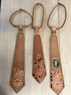 three leather ties with designs on them sitting on a table