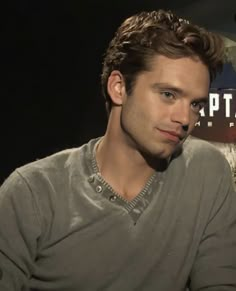 a man sitting in front of a sign with the caption captain america on it