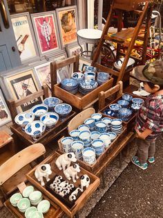 a little boy standing in front of a table filled with blue and white dishes on display