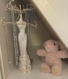 a pink teddy bear sitting next to a dress on display