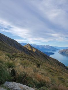 the view from the top of a mountain looking down on water and mountains in the distance