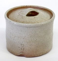 a white ceramic pot with a lid on the side and a small hole in the middle