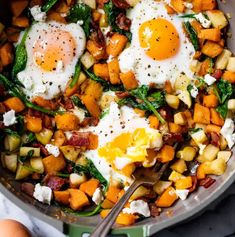 a skillet filled with eggs, potatoes and spinach on top of a table