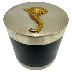 a black and silver container with a gold sea horse on it