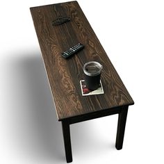 a wooden table with remote controls and a cup on it