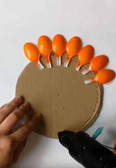 someone is making a paper turkey craft with oranges on it's head and fingers