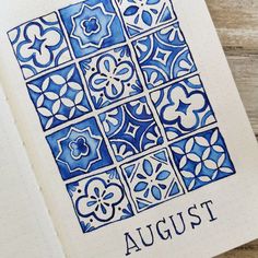 an open notebook with blue and white tiles on the cover that says august written in cursive ink