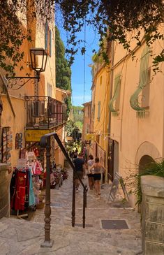 people are walking down an alleyway in the old part of town on a sunny day