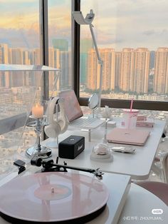 a record player sitting on top of a white table next to a window with cityscape in the background