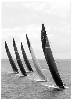 black and white photograph of four sailboats in the ocean with one boat behind them