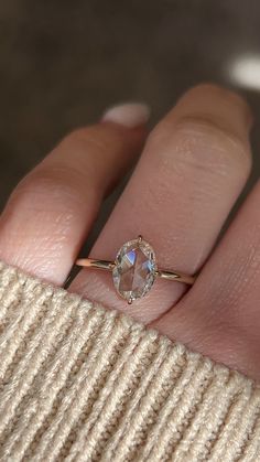 a woman's hand with a diamond ring on top of her finger, showing the side view