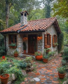 a small stone house with potted plants in the front yard and brick walkway leading up to it