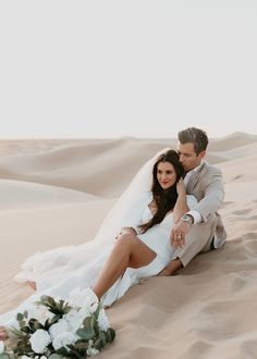 a newly married couple sitting in the desert