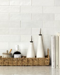 three white vases sitting on top of a shelf next to books and a book