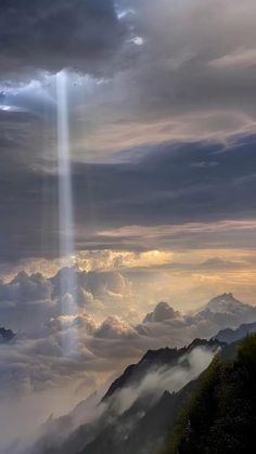 an image of the sun shining through clouds in the sky with mountains and trees below