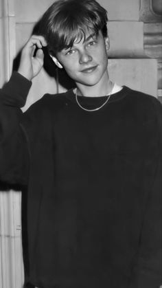 a young man wearing a black sweater and silver necklace