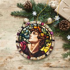 a stained glass ornament with a woman's face and pine cones on it