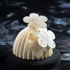 a close up of a cake on a black plate with white frosting and gold sprinkles