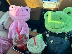 two stuffed animals are sitting in the back seat of a car with drinks and snacks